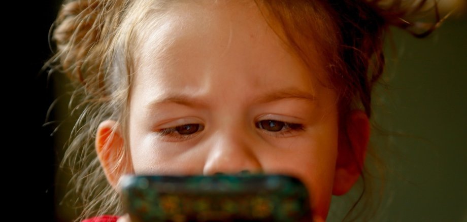 Gesicht eines kleinen Kindes vor einem Handy