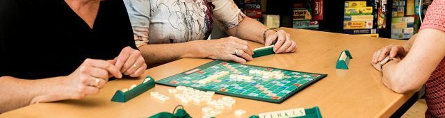 Bildausschnitt mit einem Scrabblespiel und Händen von drei Personen