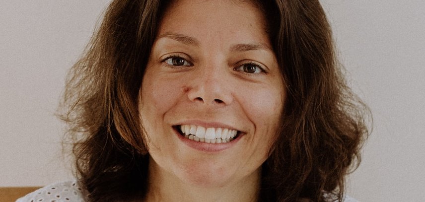 Eine Frau mit braunen halblangen Haaren lächelt in die Kamera. Es ist nur der Oberkörper zu sehen.