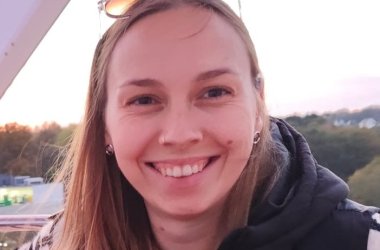 Eine junge Frau lächelt in die Kamera, von ihr ist nur der Kopf zu sehen.