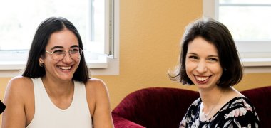 Zwei lachende Frauen mit dunklen Haaren