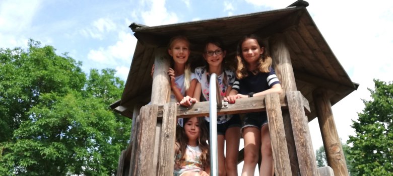 Kinder in einem Holzhaus auf dem Spielplatz