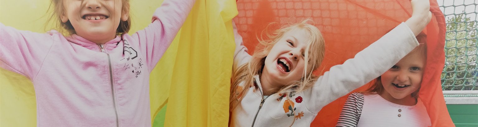 drei Kinder spielen mit einem bunten Schwungtuch